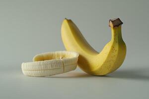 Contrast of a fresh yellow banana and its peeled counterpart against a simple background photo