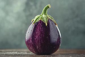 Fresh aubergine with droplets on a wooden table, illuminated by soft light indoors photo