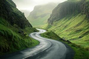Winding road through lush green hills of a misty valley during early morning light photo