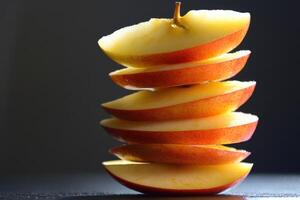 Sliced red apple stacked on a dark surface with dramatic lighting showcasing its texture photo