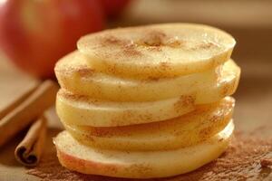 Sliced apples dusted with cinnamon on a wooden table with whole apples in the background photo