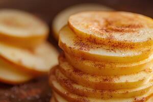 Stacked slices of apples coated with cinnamon arranged on a wooden surface in natural light photo