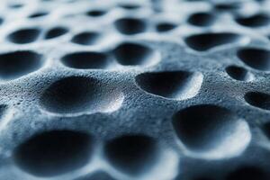 Close-up of textured surface with numerous shallow indentations and shadows under soft lighting photo