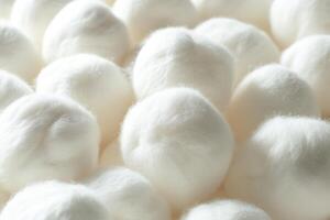 Soft, fluffy cotton balls arranged closely together on a smooth surface indoors photo