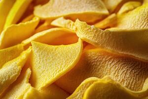 Yellow dried mango slices on a textured surface create a vibrant and tasty snack display photo