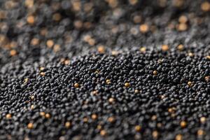 Close-up view of scattered black mustard seeds on a textured surface at a farmer's market photo