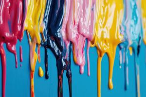 Colorful drips of paint creating an artistic display on a blue wall during a creative project photo