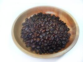 dish of roasted coffee beans on brown wood plate isolated on white background with copy space photo
