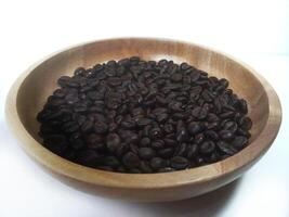 dish of roasted coffee beans on brown wood plate isolated on white background with copy space photo
