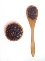 Roasted coffee bean on small wooden bowl and spoon isolated on white background with copy space photo
