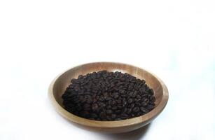 dish of roasted coffee beans on brown wood plate isolated on white background with copy space photo
