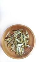 Ikan asin or dried salted fish on brown wood plate isolated on white background with copy space photo