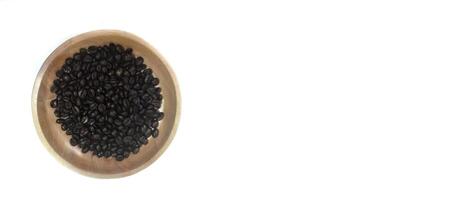 dish of roasted coffee beans on brown wood plate isolated on white background with copy space photo