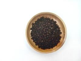 dish of roasted coffee beans on brown wood plate isolated on white background with copy space photo