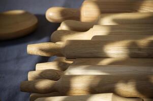 Wooden rolling pins neatly arranged on a table, casting shadows in soft natural light photo