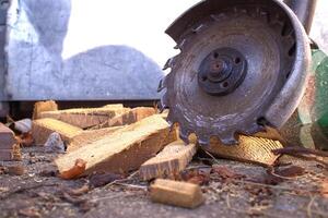 Circular saw blade slices through logs, scattering wood shavings and debris around a rustic workshop photo