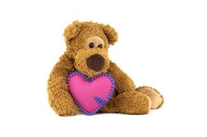 Teddy bear holding pink heart with blue stitching, expressing love and warmth on a white background photo