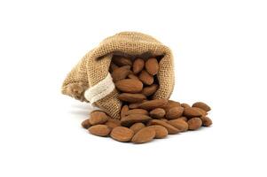 Rustic burlap sack overflowing with fresh almonds isolated on white background photo