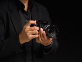 Close-up of hand holding the digital camera while standing on a black background photo