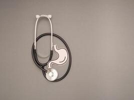 A stethoscope and stomach shape made from paper are over a gray background photo