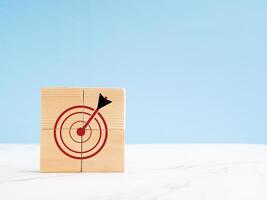 Darts target icon on wooden cubes on the marble floor with a light blue background photo