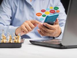Close-up of hands using mobile phone with colorful chat icons on the application photo