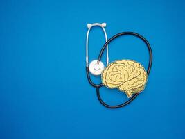 A stethoscope and brain shape made from paper over a blue background photo