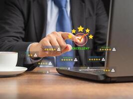 Businessman in a suit touching on the five-star icon to give a rating of excellent photo