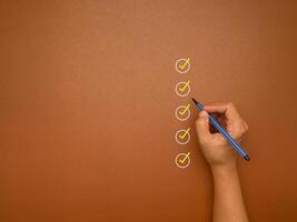 Checklist concept. Yellow marking on checklist box over a brown background photo