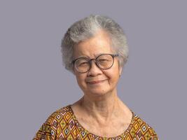 Portrait of a senior woman with short gray hair looking at the camera with a smile while standing on gray background photo