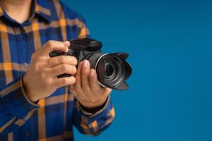 Close-up of hands holding the digital camera while standing on a blue background photo