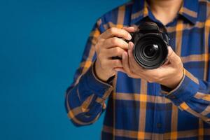Close-up of hand holding the digital camera while standing on a blue background photo