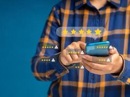 Man using a smartphone give the five-star icon a rating of very impressed for service. Customer service and satisfaction surveys concept photo