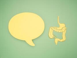 Yellow speech bubble and large intestine shape made from yellow paper over a green background photo