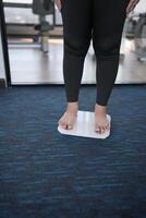 Fat diet and scale feet standing on electronic scales for weight control. Measurement instrument in kilogram for a diet control. photo