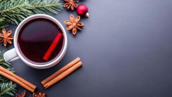 White mug of mulled wine with cinnamon, anise stars and Christmas tree branches on dark background. Top view, copy space. photo