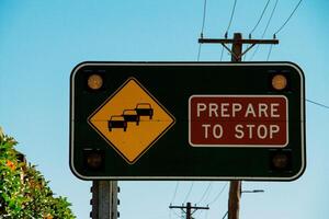 Prepare To Stop Traffic Sign With Flashing Lights Along A Busy Road Under A Bright Blue Sky photo