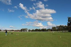 Wide Green Grass Field Under Clear Blue Sky With Clouds And Football Training photo