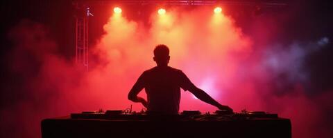 DJ performing with vibrant red and blue stage lights in a smoky atmosphere photo