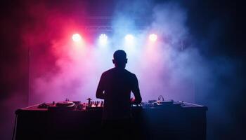 DJ performing with vibrant red and blue stage lights in a smoky atmosphere photo