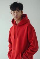 A young korean man wearing a red hoodie with hands in pockets photo