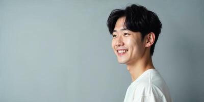 Smiling Young Korean Man in White T-Shirt, Side Profile Against Gray Background, copy space photo