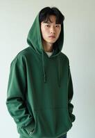 Young korean man in a green hoodie looking at the camera photo