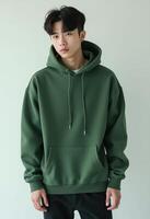 Young korean man in green hoodie. poses confidently against white background photo