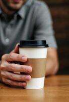Man holding a takeaway coffee cup in a relaxed setting photo