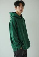 Young korean man in a green hoodie looking at the camera photo