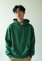 Young korean man wearing a forest green hoodie poses confidently photo
