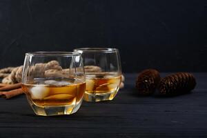 Glass of whiskey with ice on dark background photo