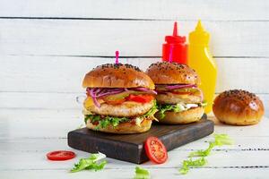 Burger with chicken cutlet, tomatoes, pickle and lettuce. Delicious homemade burger photo