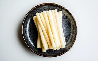 View of delicious string cheese on a plate over a white background photo